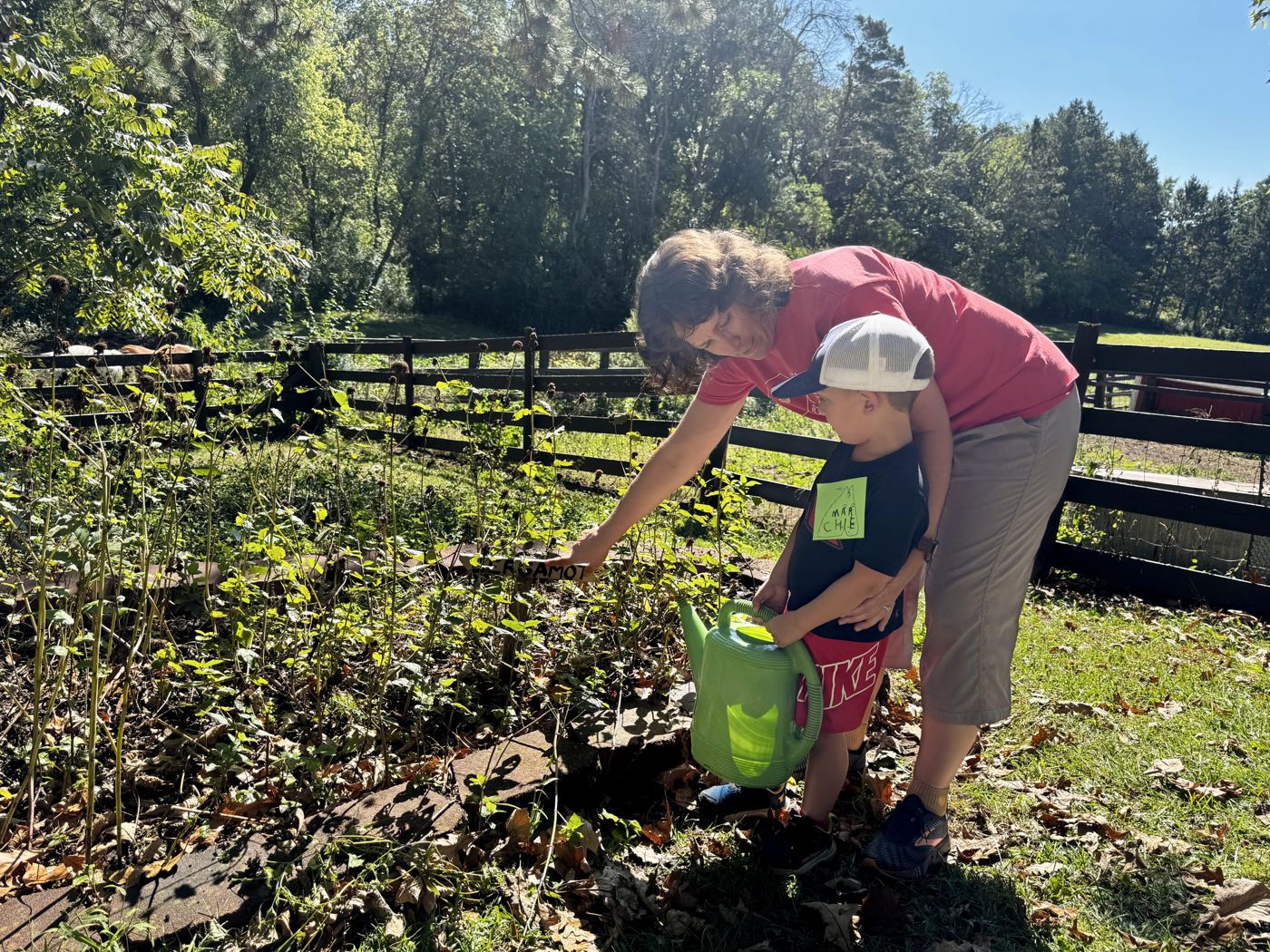 Jenny Peterson helping a young child water a garden